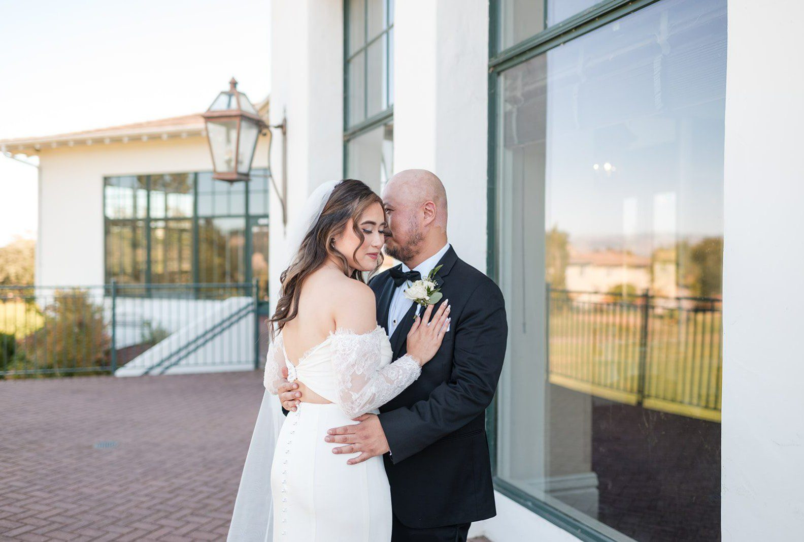 Bride and groom embracing by the clubhouse windows, captured by San Francisco wedding photographers from Original Weddings at Eagle Ridge