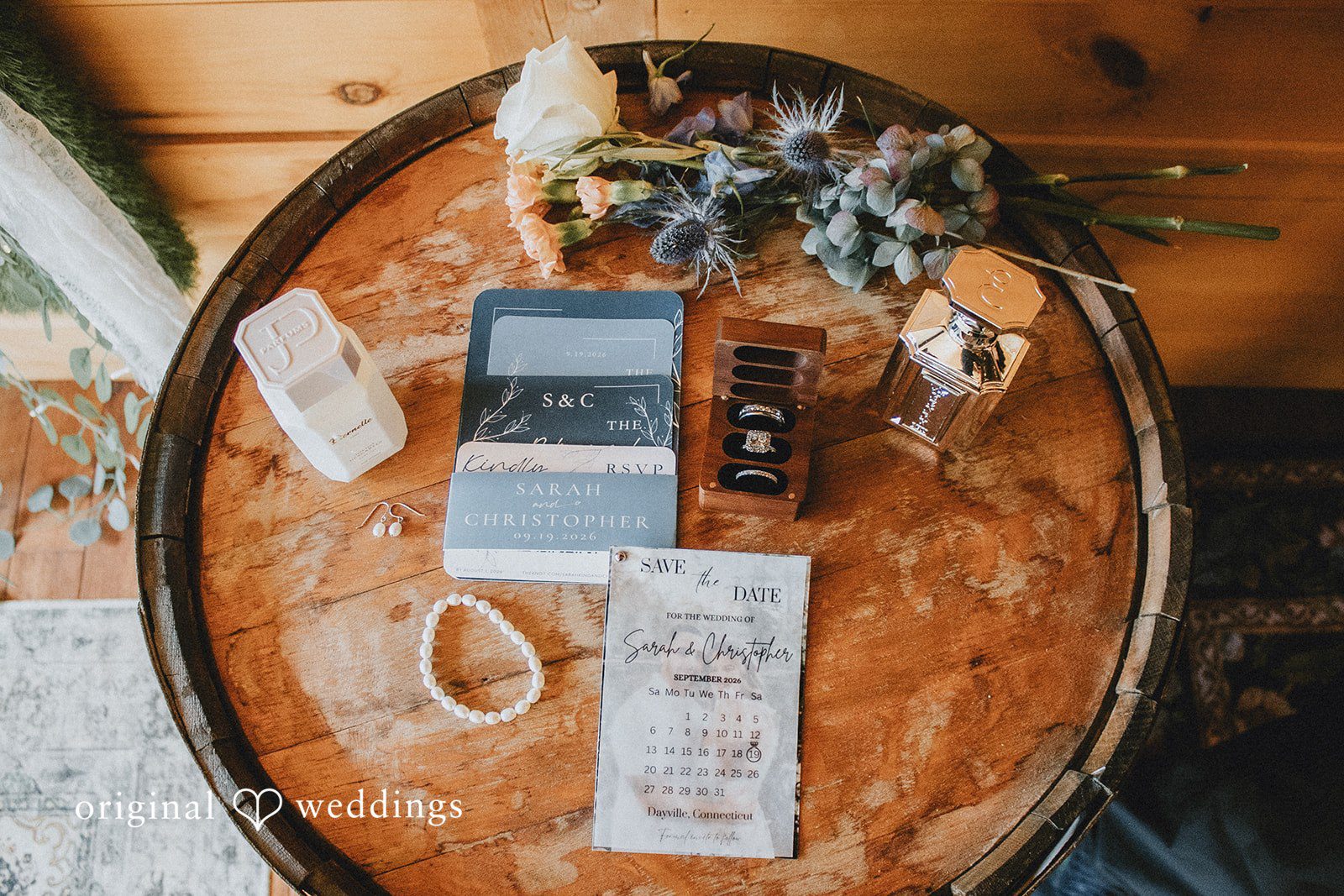 September 19, 2026 – Sarah & Christopher – (ID-4569) Flat-lay detail shots including invitations, rings, and decorative greenery displayed on a tray.