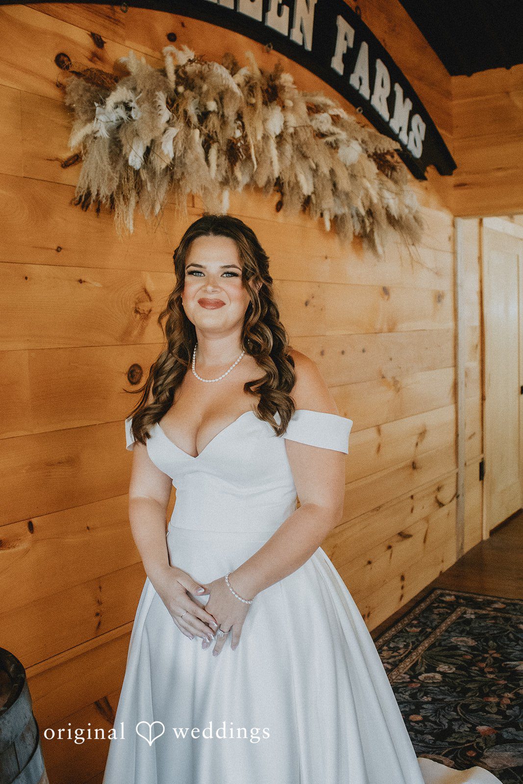 Sarah + Christopher A bride in a white gown posing against a wooden interior background.