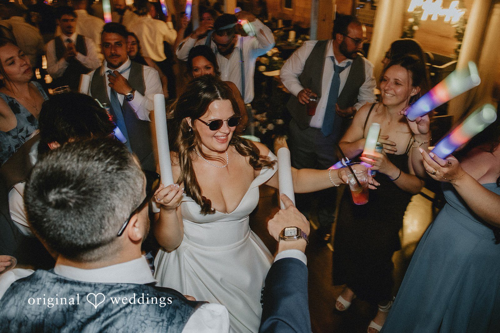 Sarah + Christopher Guests dancing and holding glow sticks on the dance floor.