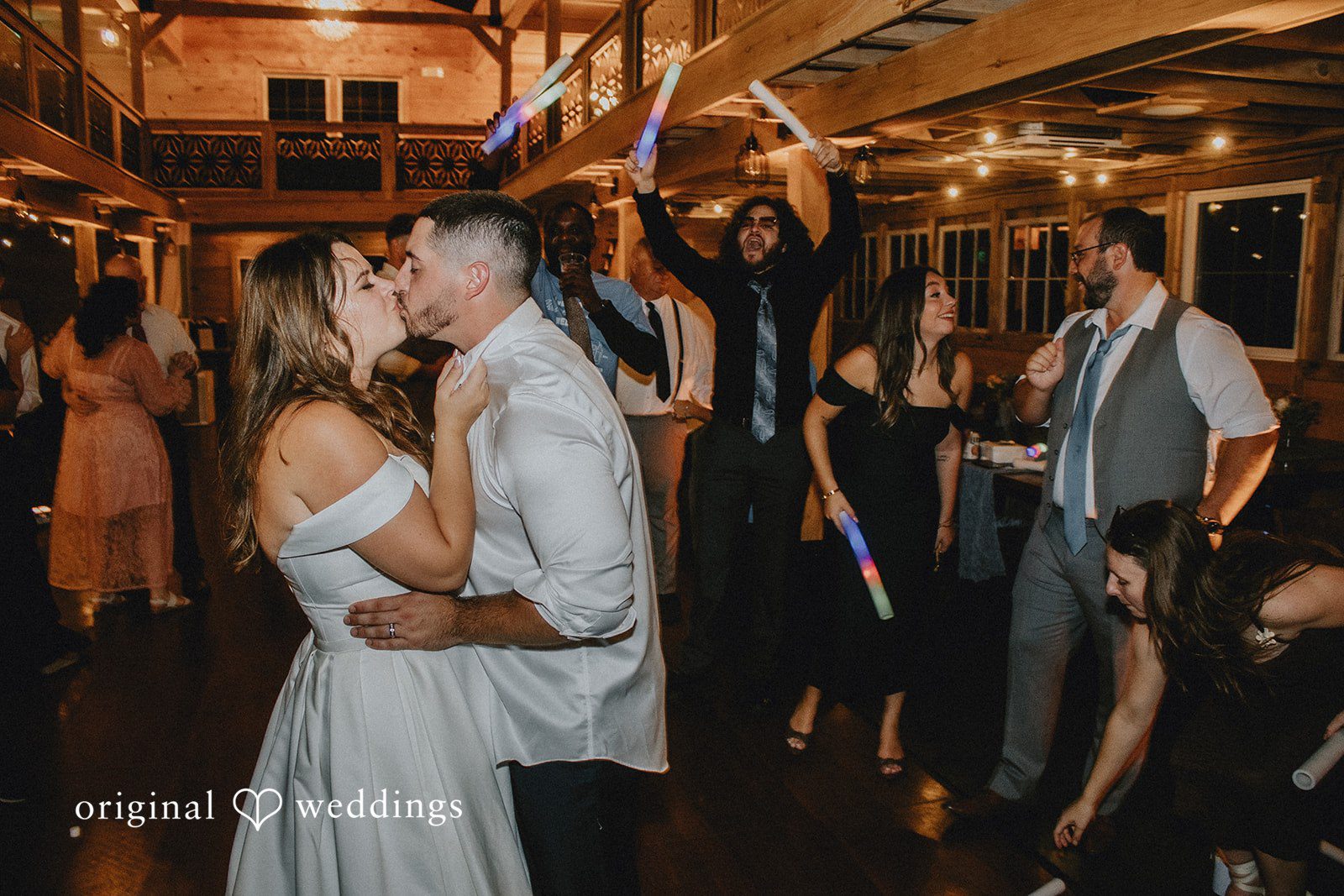 Sarah + Christopher A bride and groom sharing a kiss on a crowded dance floor.