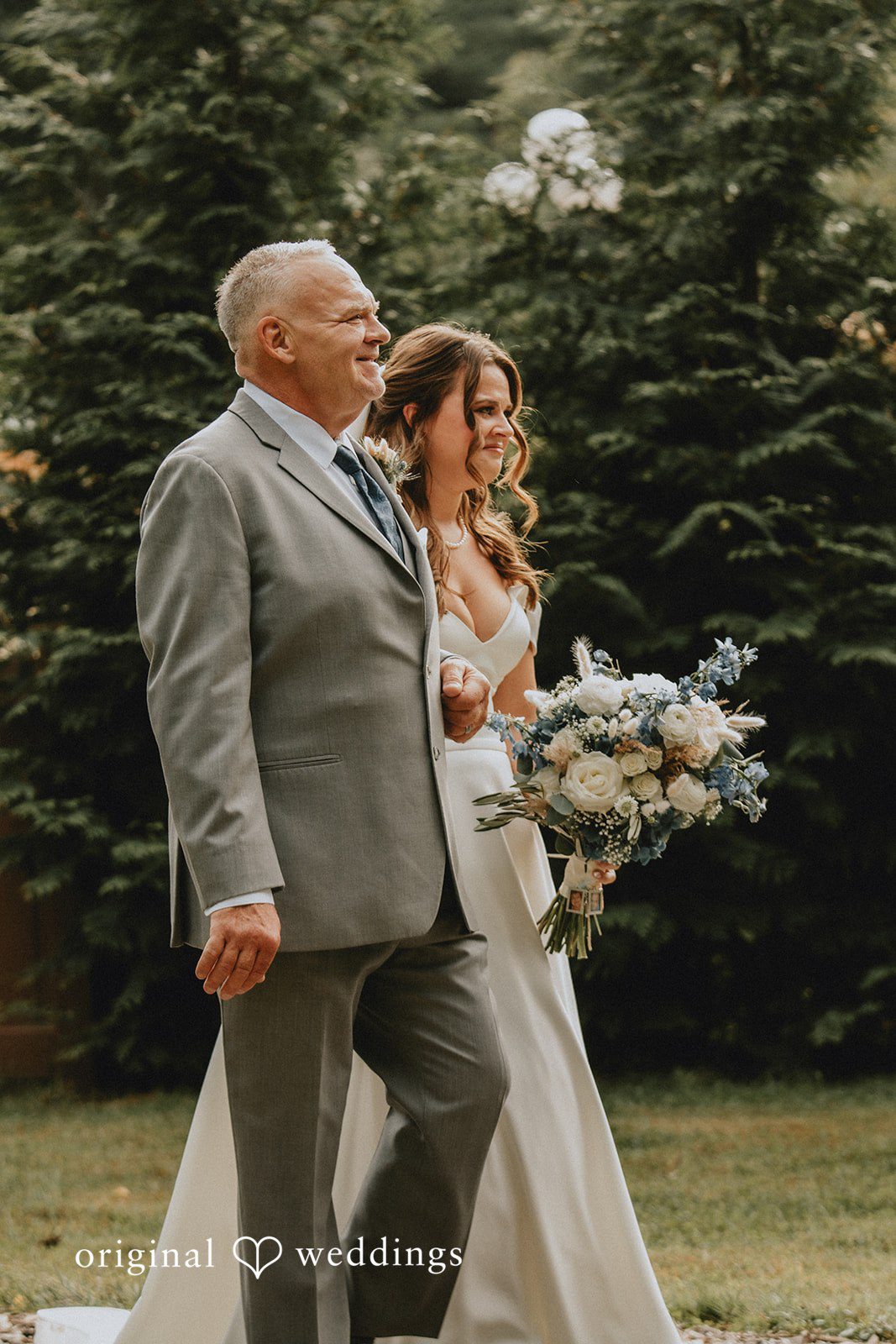 Sarah + Christopher A man in a gray suit walking together alongside a bride in a white gown.
