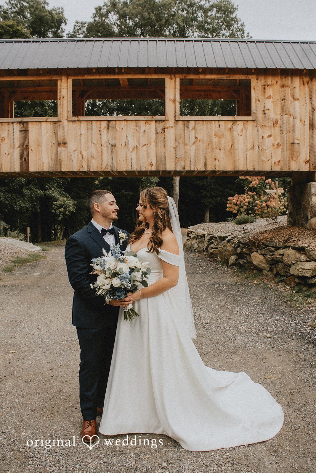 Sarah + Christopher A bride and groom standing together near a wooden structure.