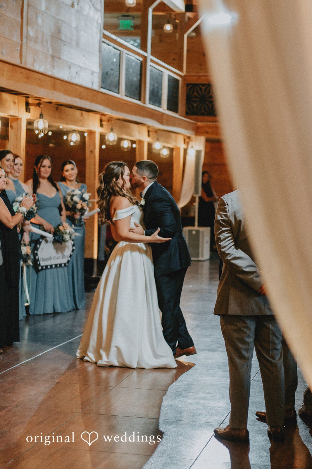 Sarah + Christopher A bride and groom dancing together in the center of a rustic hall.