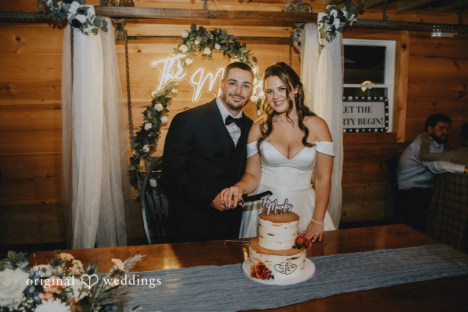 Sarah + Christopher A bride and groom standing together behind a small wedding cake.