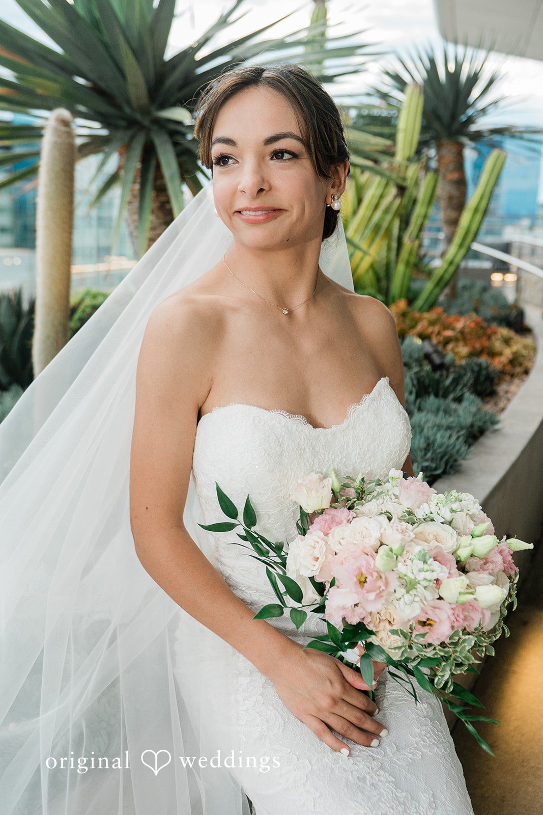 Bride holding her bouquet beside the palms