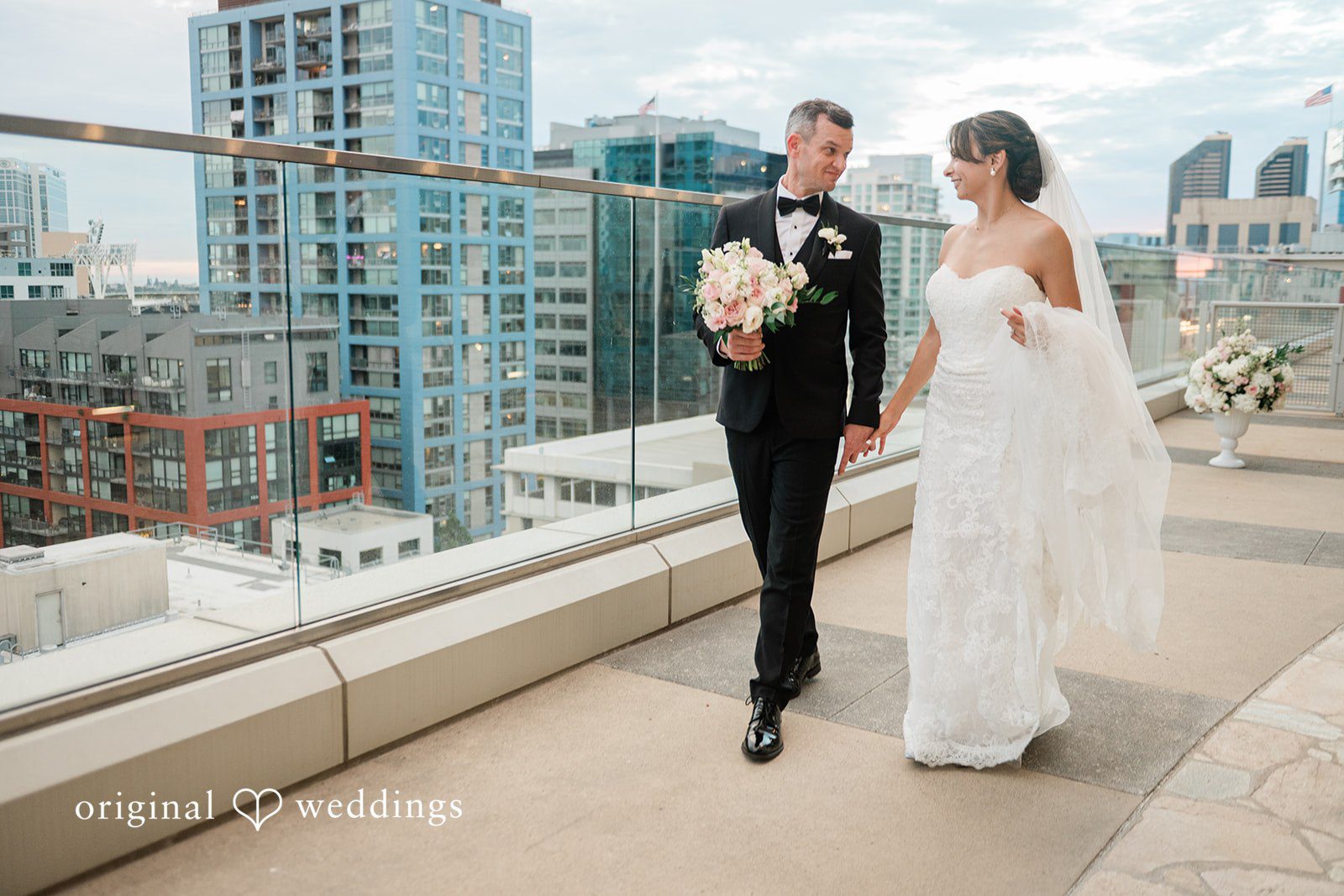 Bride and groom walking along the rooftop, captured by San Diego wedding photographers from Original Weddings