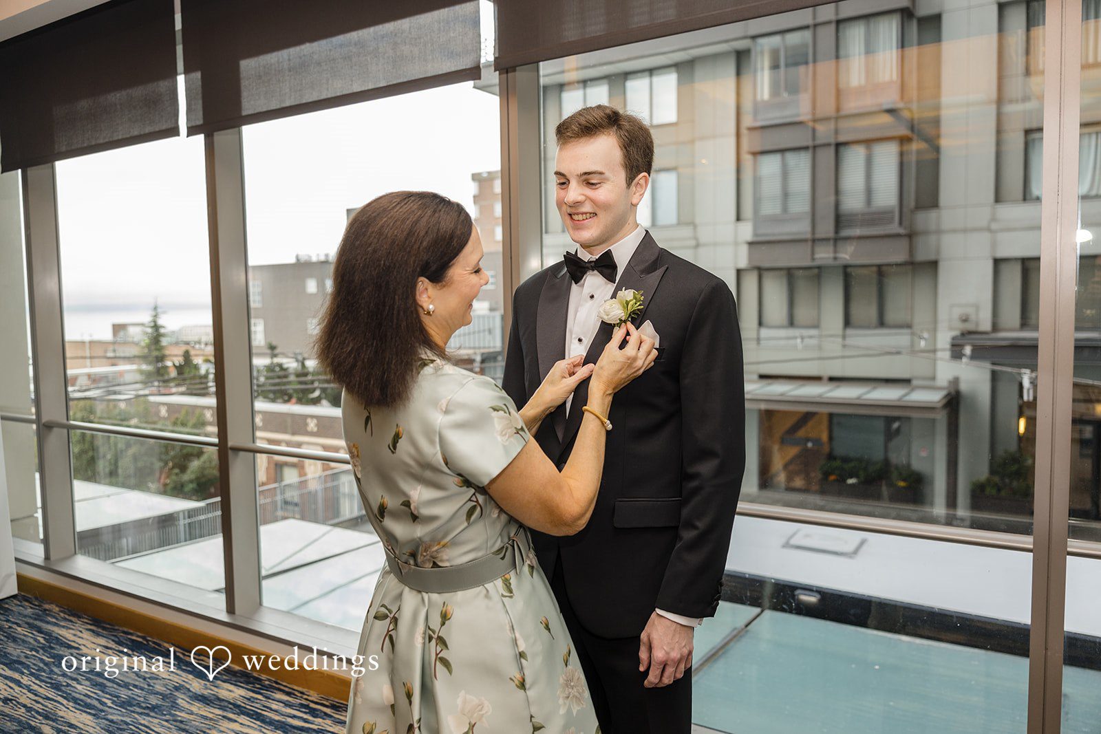 John + Michelle Groom and woman in formal attire sharing a glance near a large window.