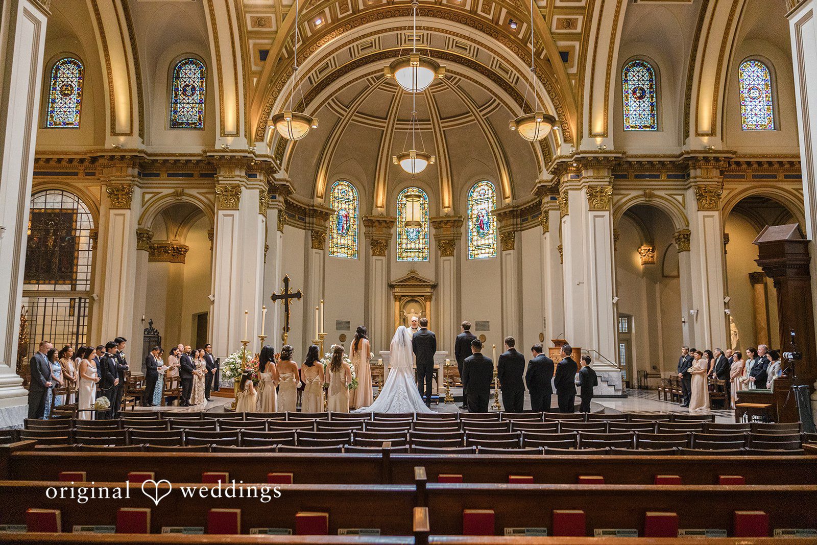 John + Michelle Wide perspective of a wedding ceremony taking place inside a historic cathedral.