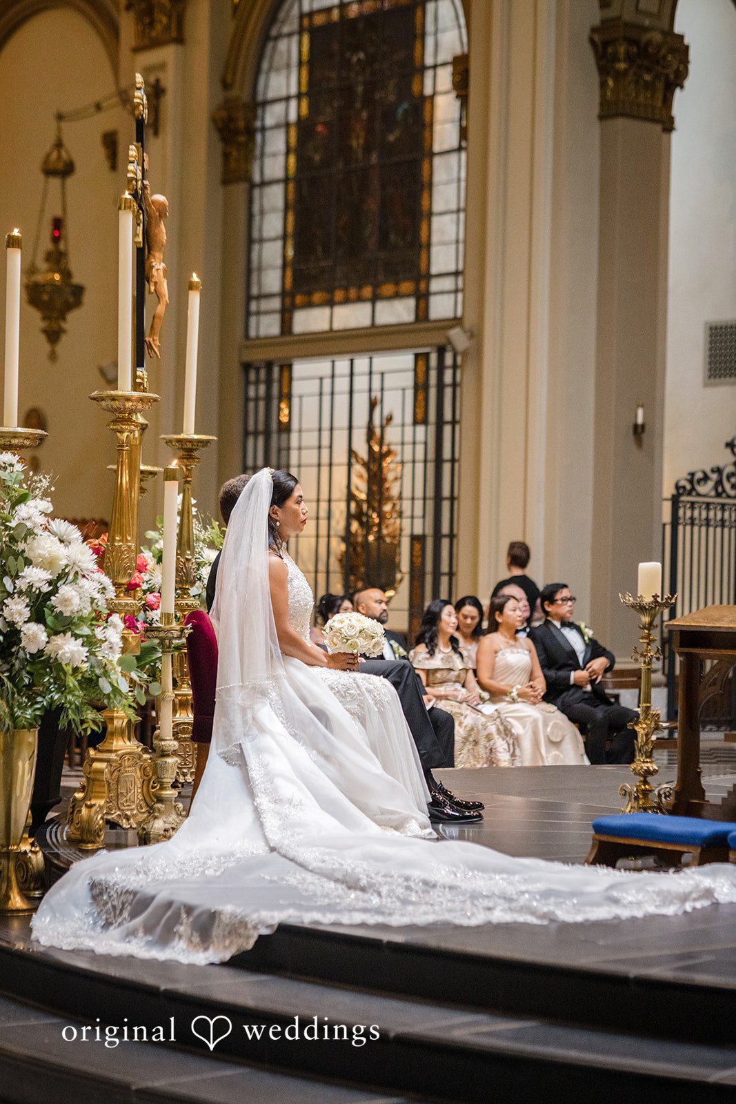 John + Michelle Bride in a flowing white dress trailing down wide church steps.