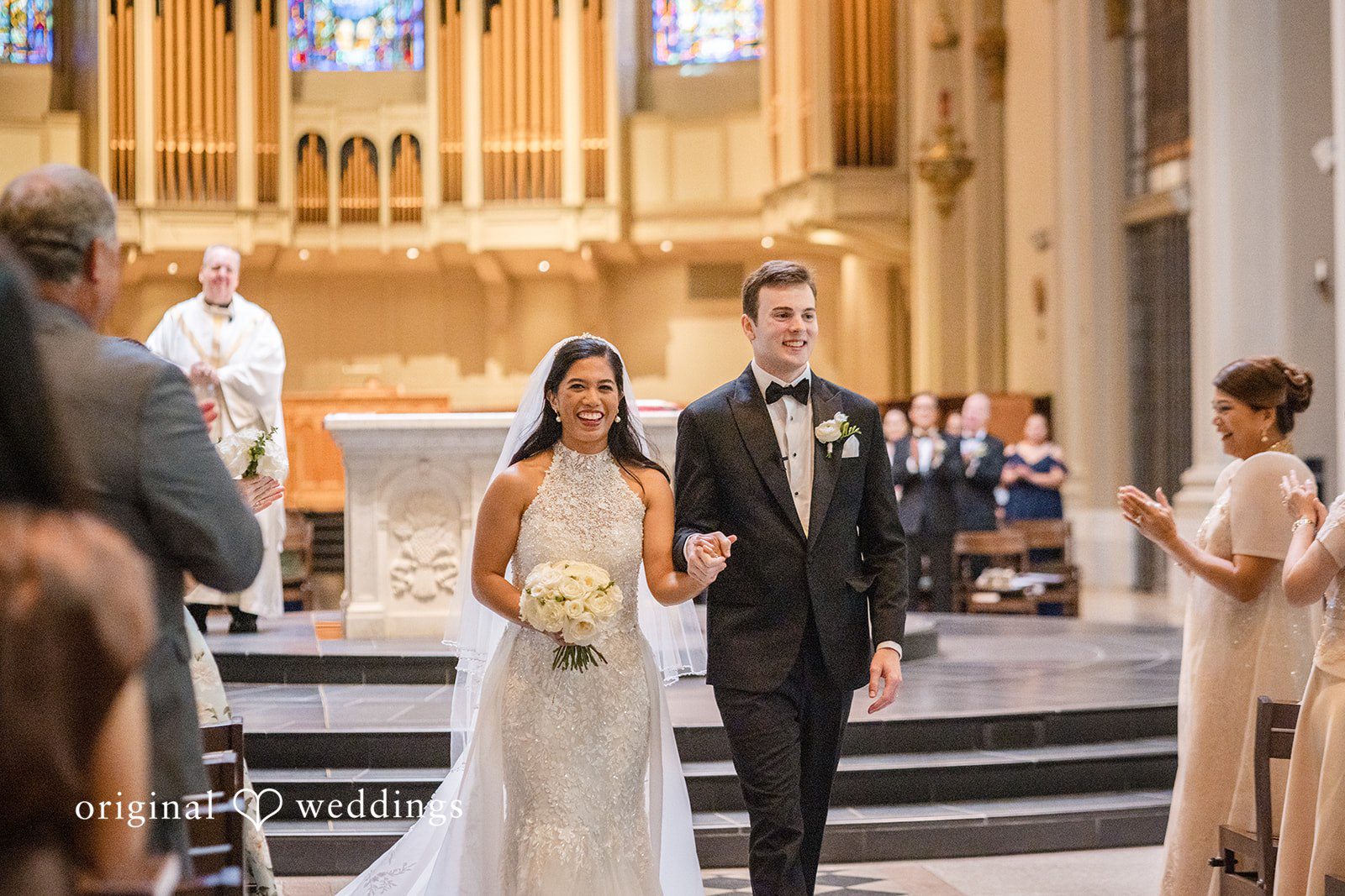 John + Michelle Bride and groom walking together through a historic church building.