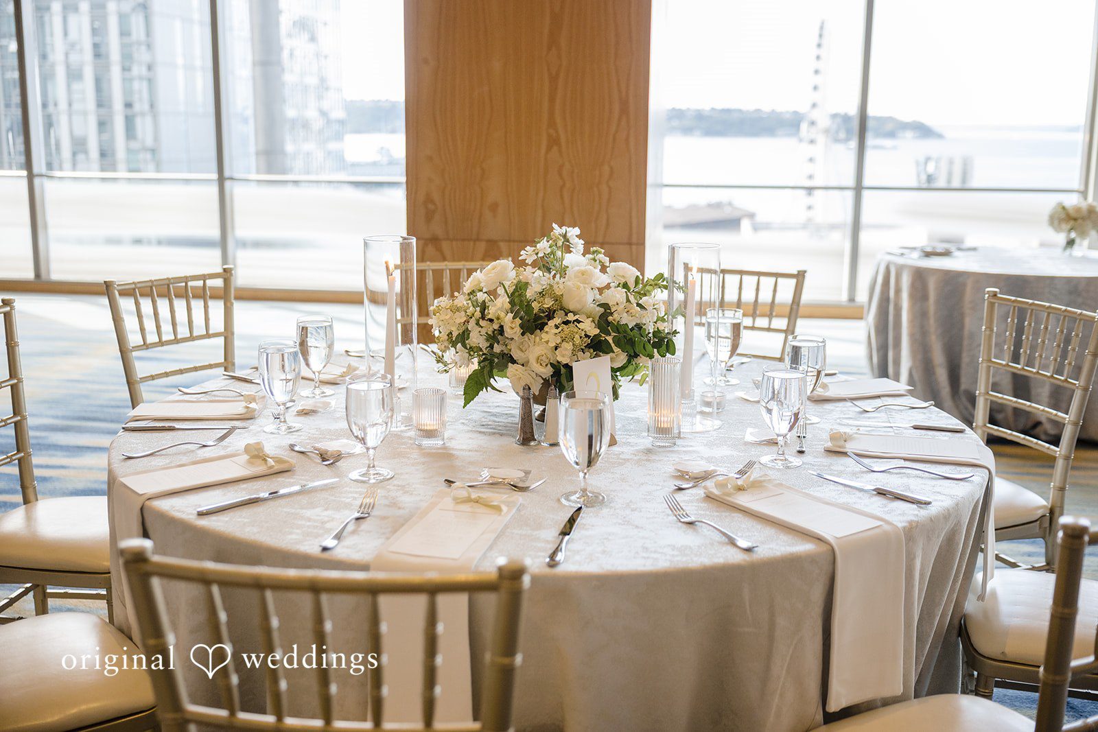 John + Michelle Detailed view of a decorated round reception table with white floral centerpieces.