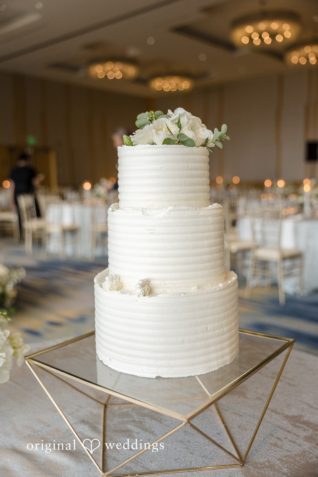 John + Michelle Multi-tiered white wedding cake displayed on a decorated table.