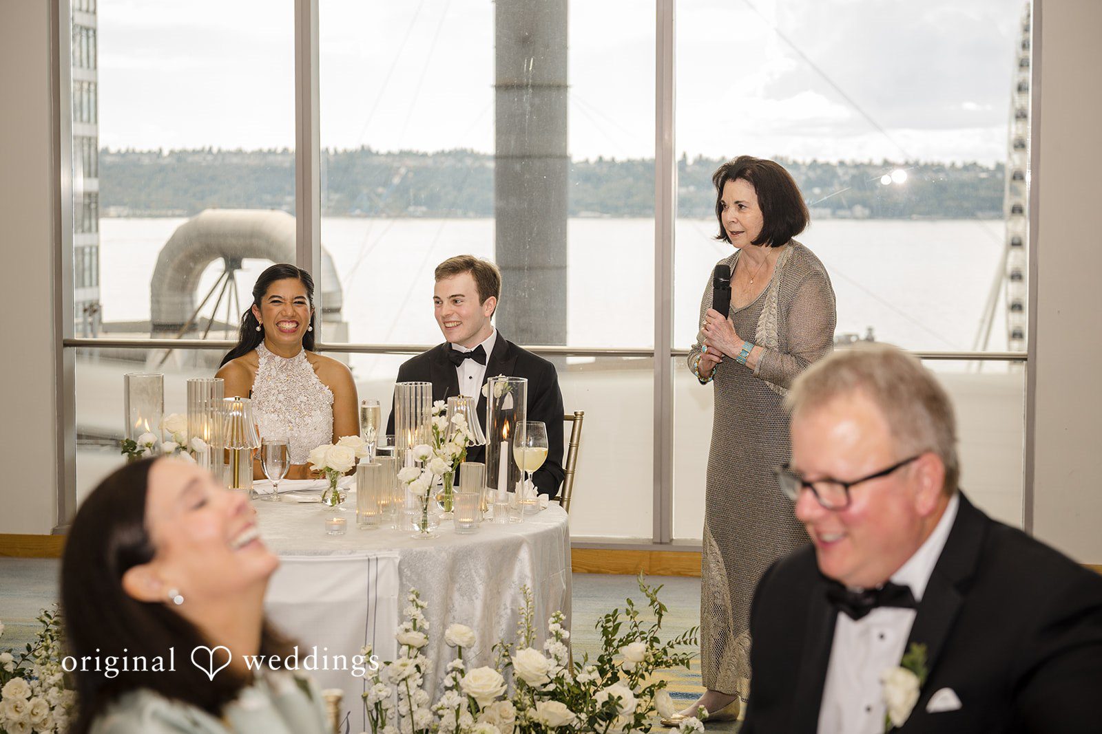 John + Michelle Man in glasses seated at a dinner reception table with other guests visible behind him.