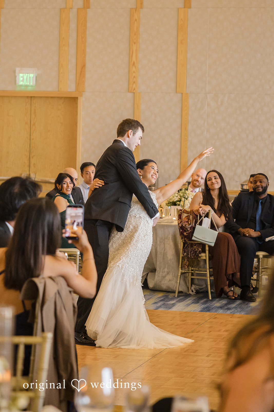 John + Michelle Bride and groom dancing enthusiastically on the reception dance floor surrounded by seated guests.