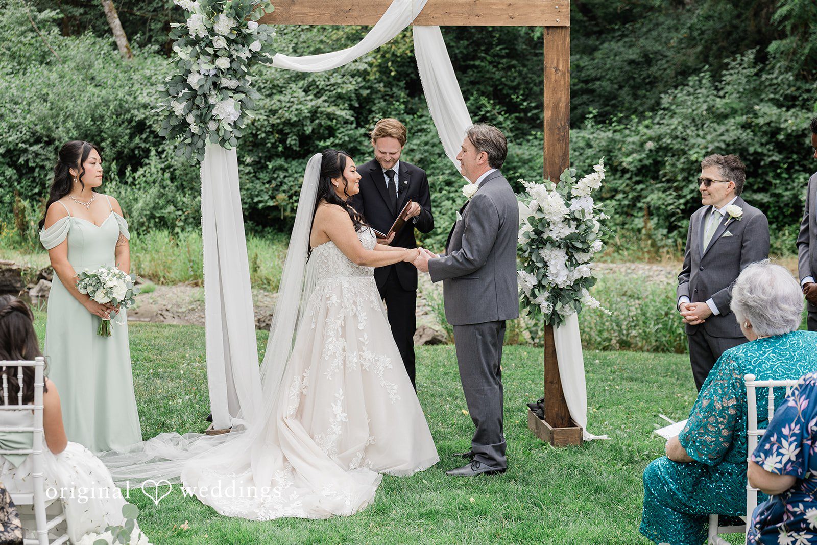 Kim + Keven A bride and groom standing under a decorated wooden arch.