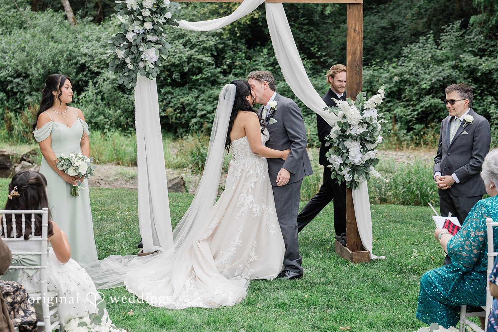 Kim + Keven A bride walking toward the groom under a draped arch.