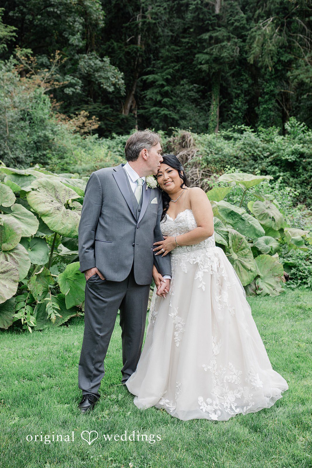 Kim + Keven A bride and groom embracing on a green lawn.