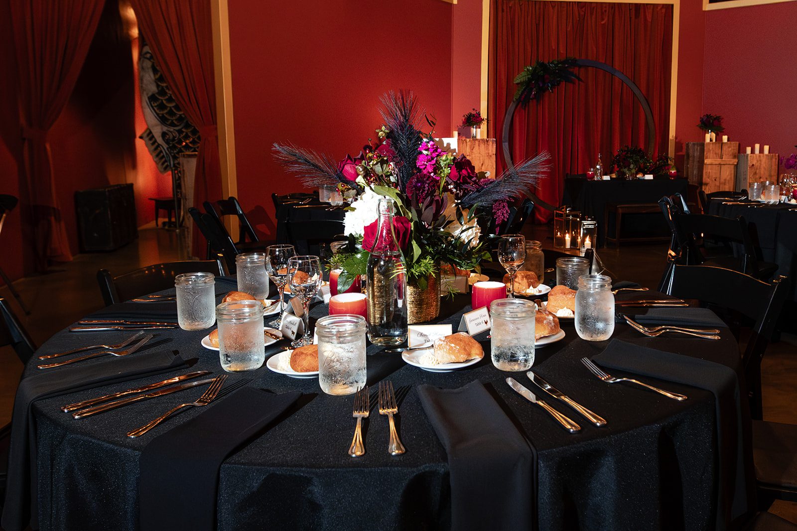 Table setting with dark linens and red flowers Table setting with dark linens and red flowers
