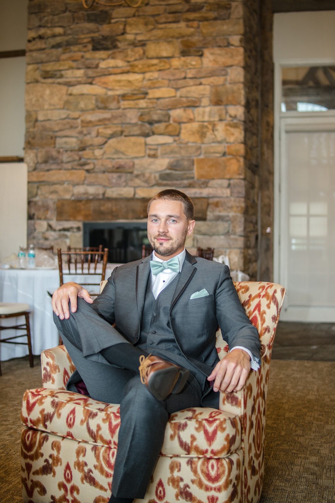 Groom relaxing by the stone fireplace