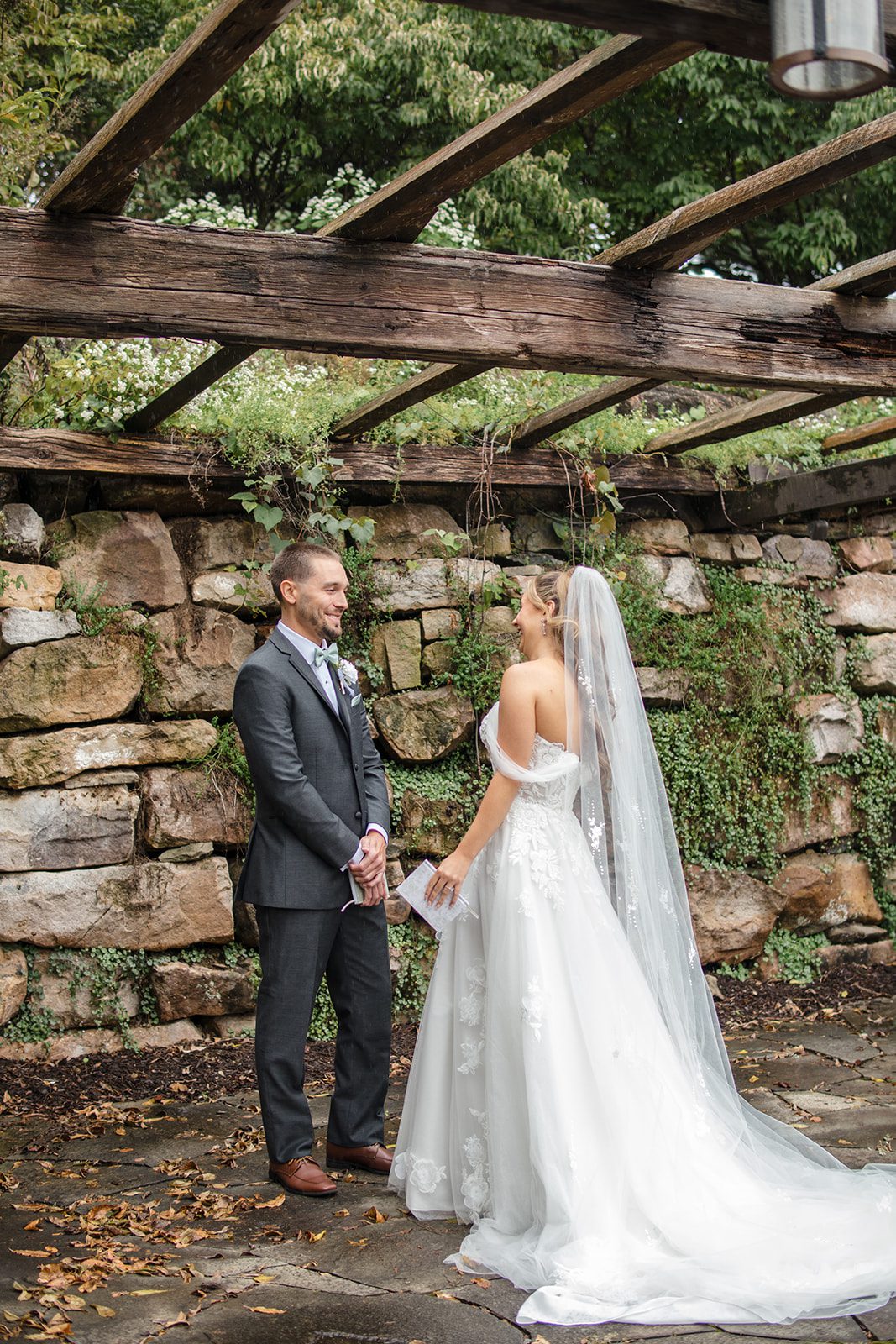 Bride surprising the groom by the stone wall