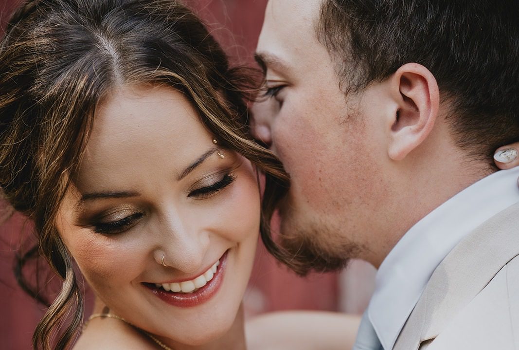 Madelyn and David sharing a sweet moment by the red barn, captured by Minneapolis wedding photographers from Original Weddings at Good Tree Farmstead