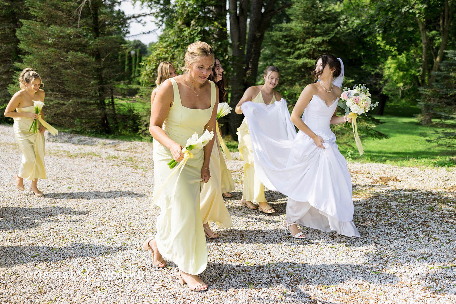 Ethan + Kelcy Bride with bridesmaids walking on a gravel path