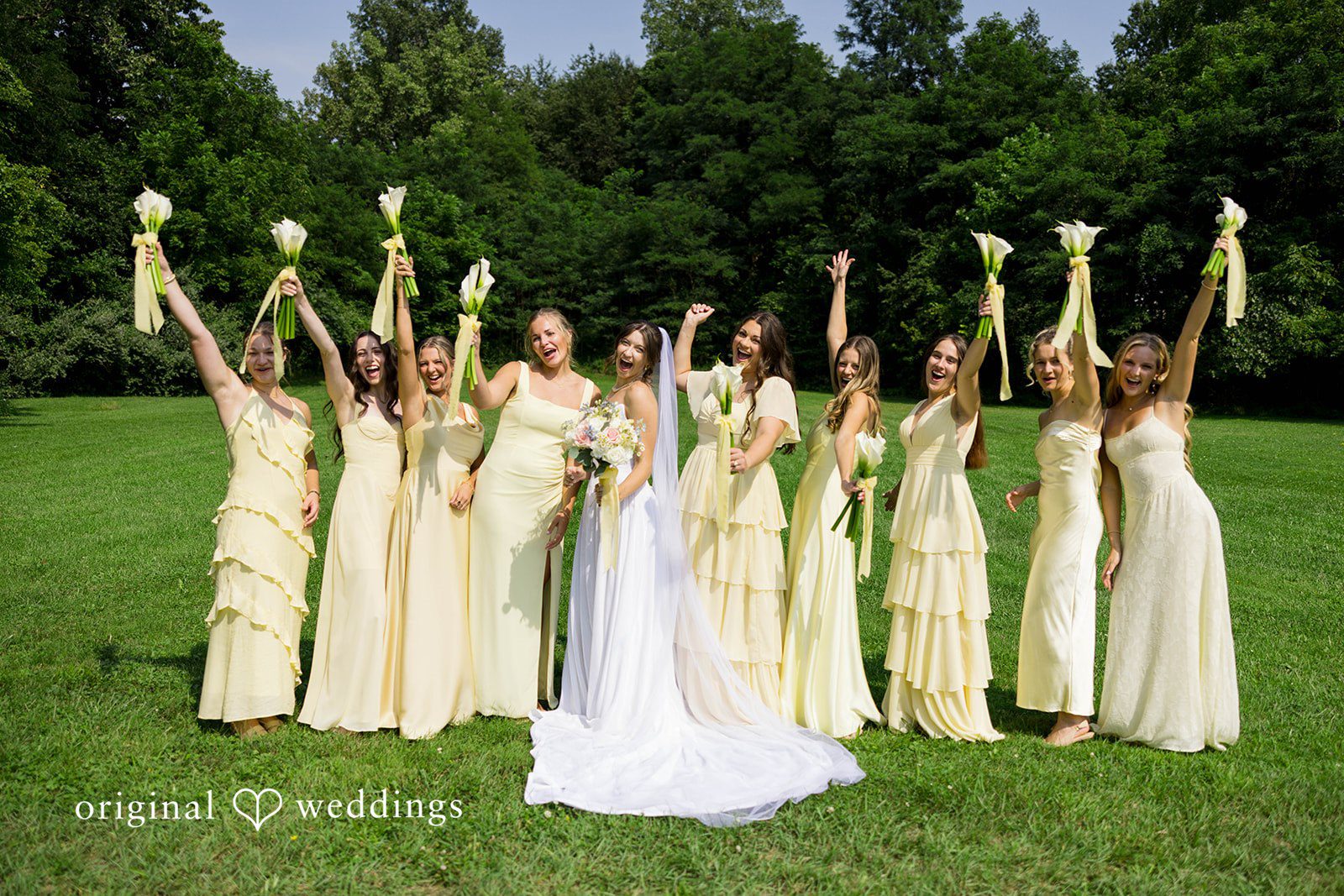 Ethan + Kelcy Bride and bridesmaids raising their bouquets on the lawn