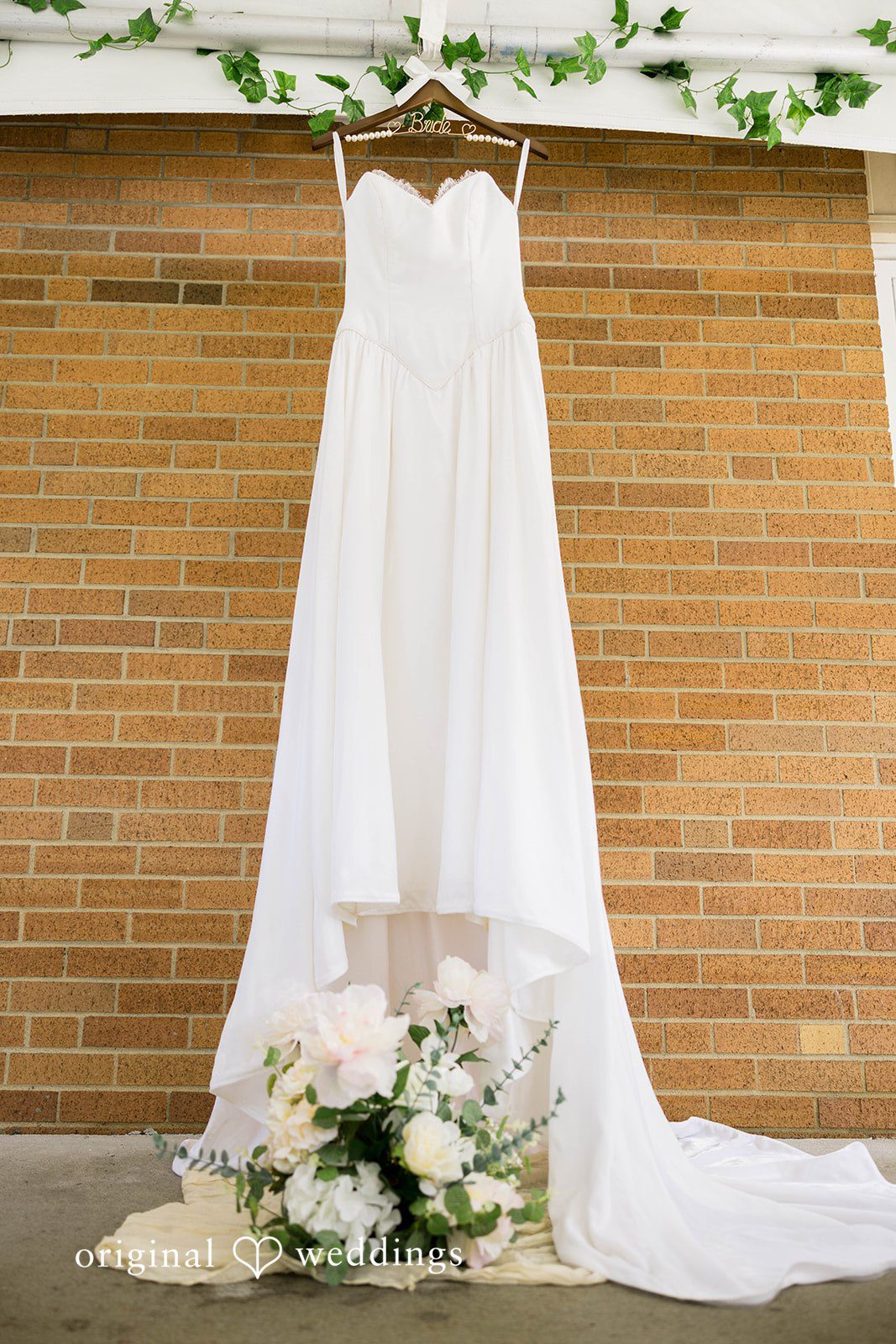 Ethan + Kelcy Wedding dress hanging on a brick wall at Grace Church Barberton