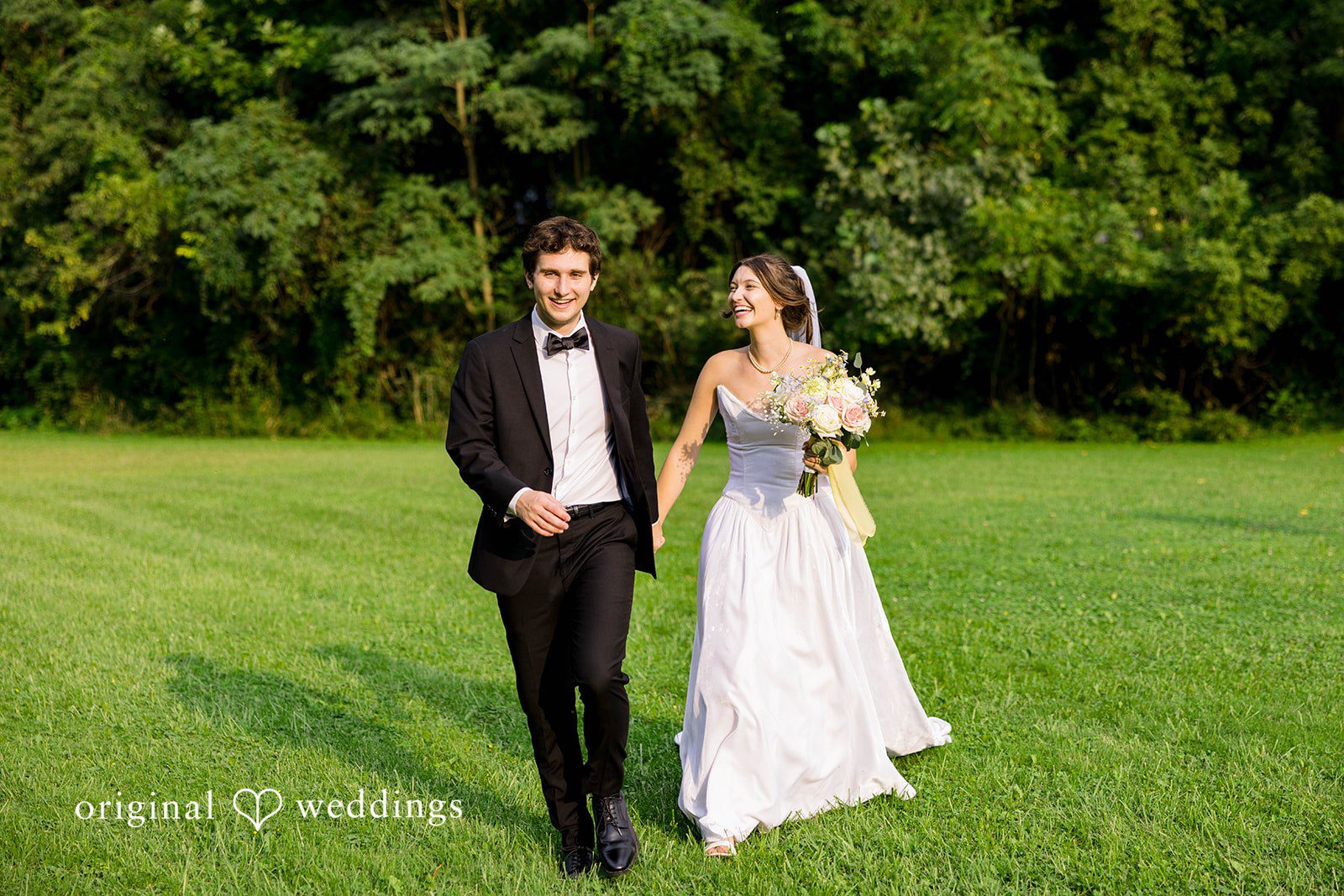 Ethan + Kelcy Couple walking hand in hand across the lawn, captured by Cleveland wedding photographers from Original Weddings at Grace Church Barberton