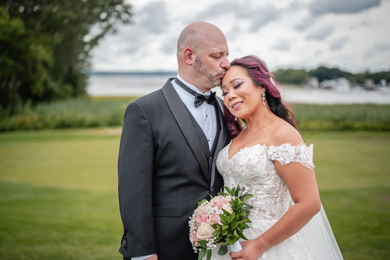 harbor-lights-timeless-providence-feng-donald-p039-40 Bride and groom smiling together on the waterfront lawn, captured by Providence wedding photographers from Original Weddings at Harbor Lights