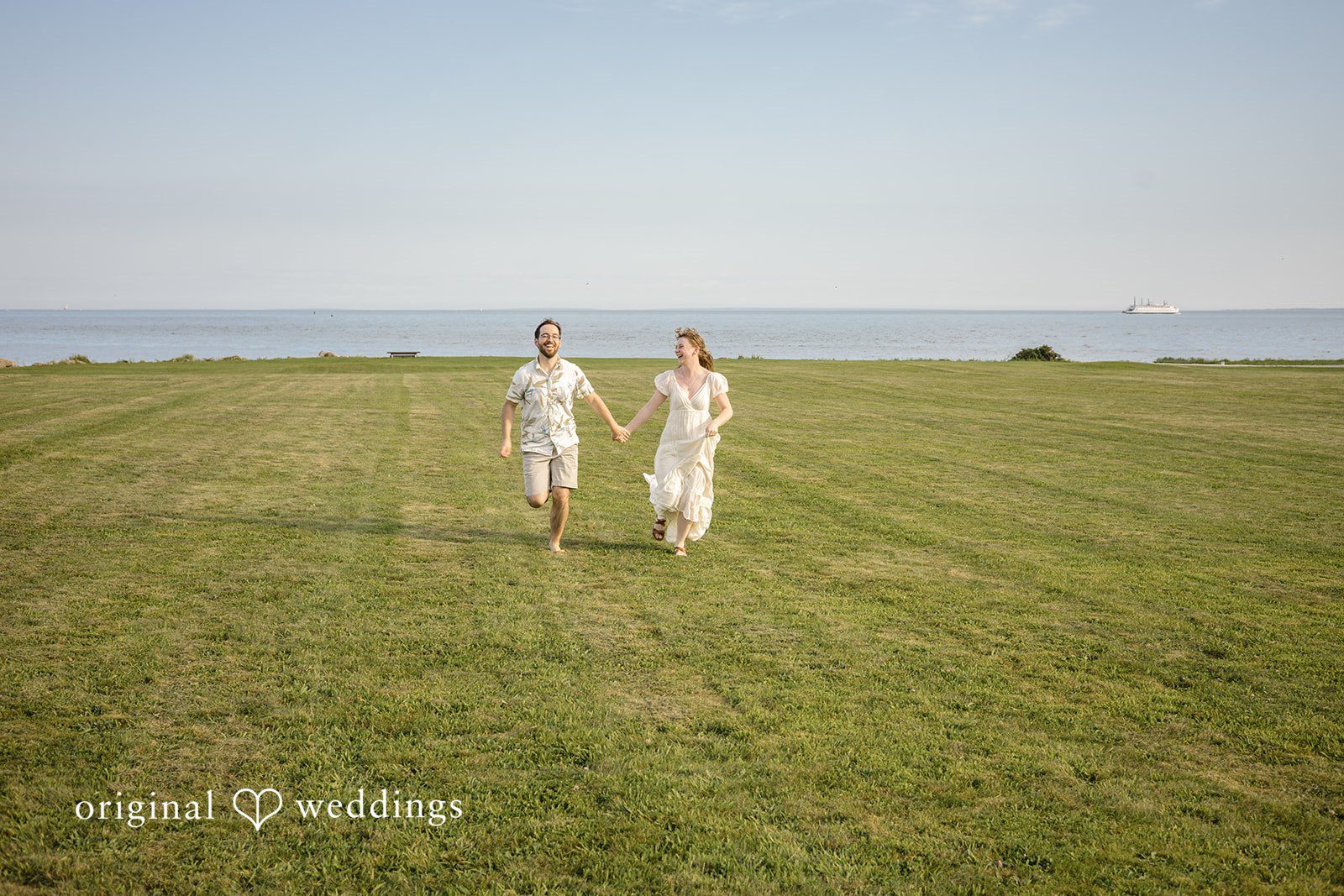 James + Ashlan Couple walk far away across a wide, open grassy lawn.