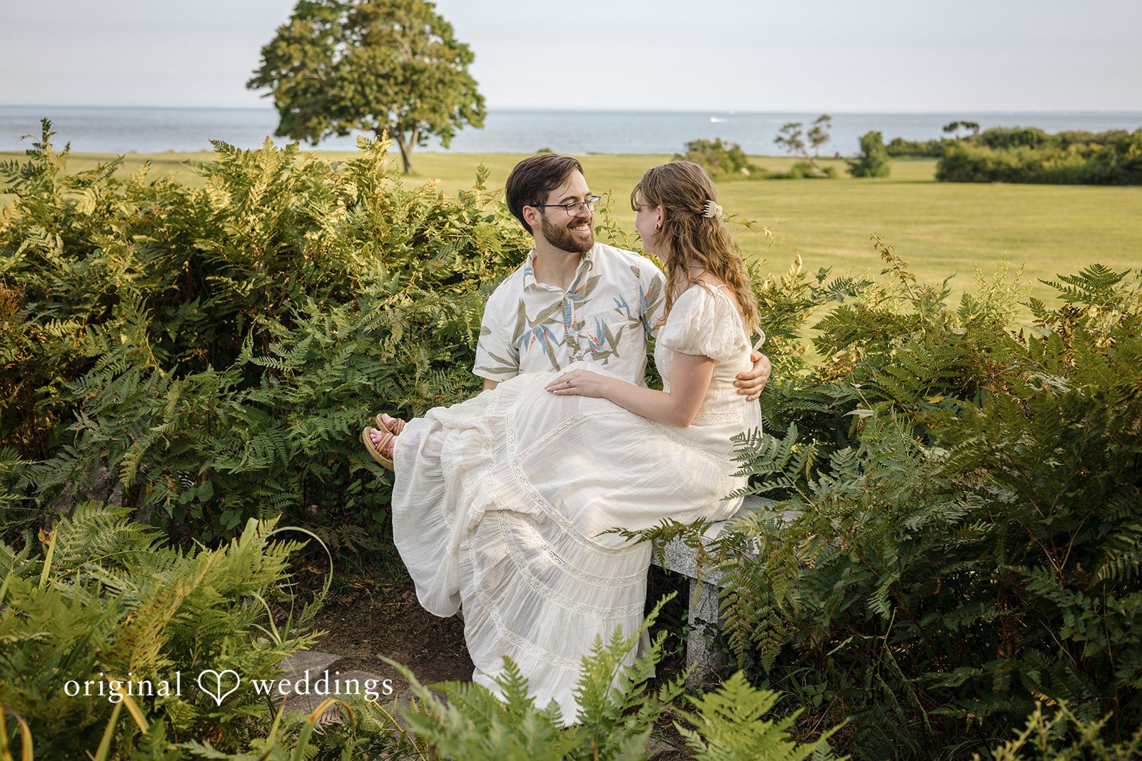 James + Ashlan A man and a woman stand together along a path lined with tall greenery.