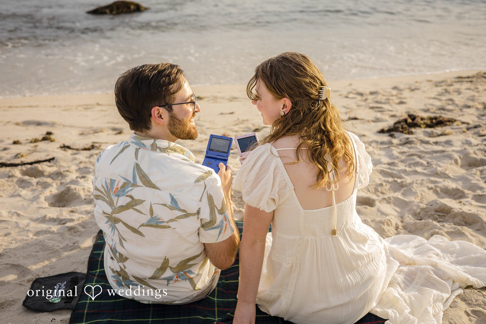 James + Ashlan A man and a woman sit together on a sandy beach.