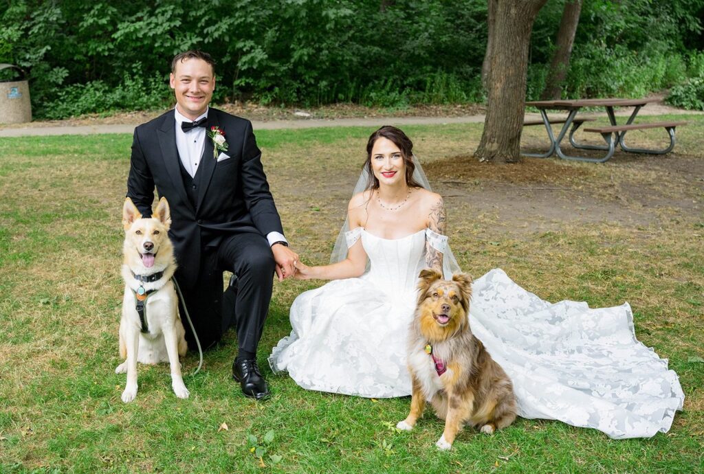Dakota and Evan smiling on the lawn with their two dogs, captured by Milwaukee wedding photographers from Original Weddings at Hubbard Park Lodge