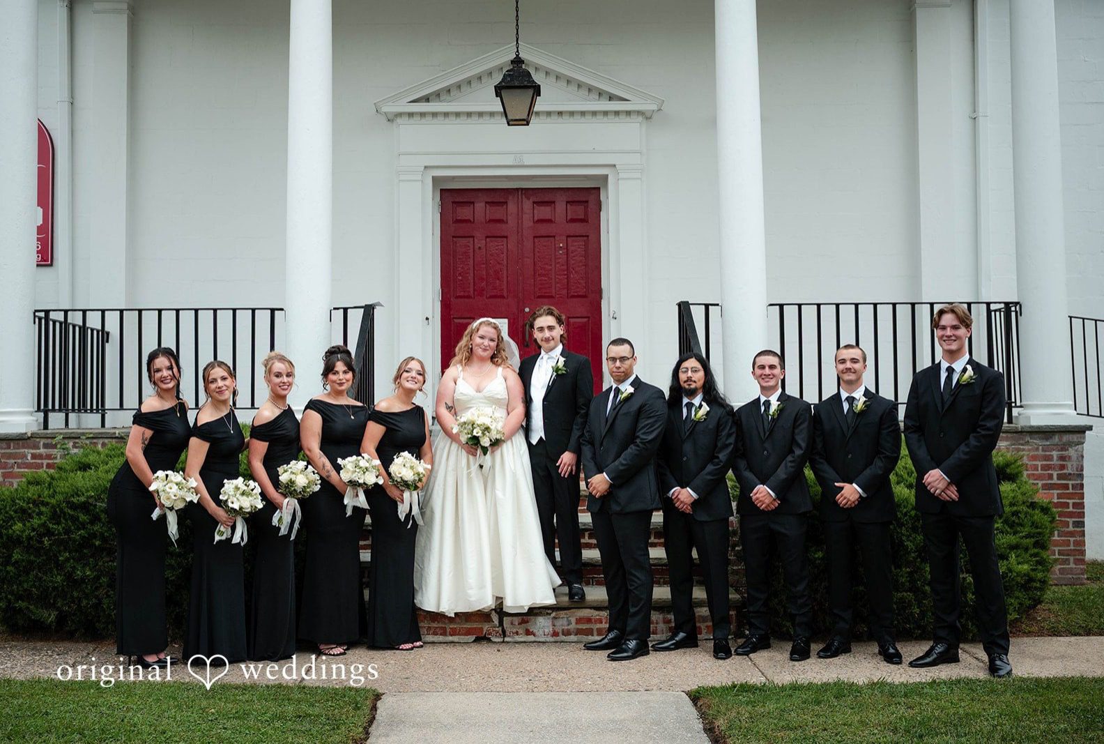 Bride, groom and their wedding party in front of the red church doors, captured by Philadelphia wedding photographers from Original Weddings at Immanuel Orthodox Presbyterian Church
