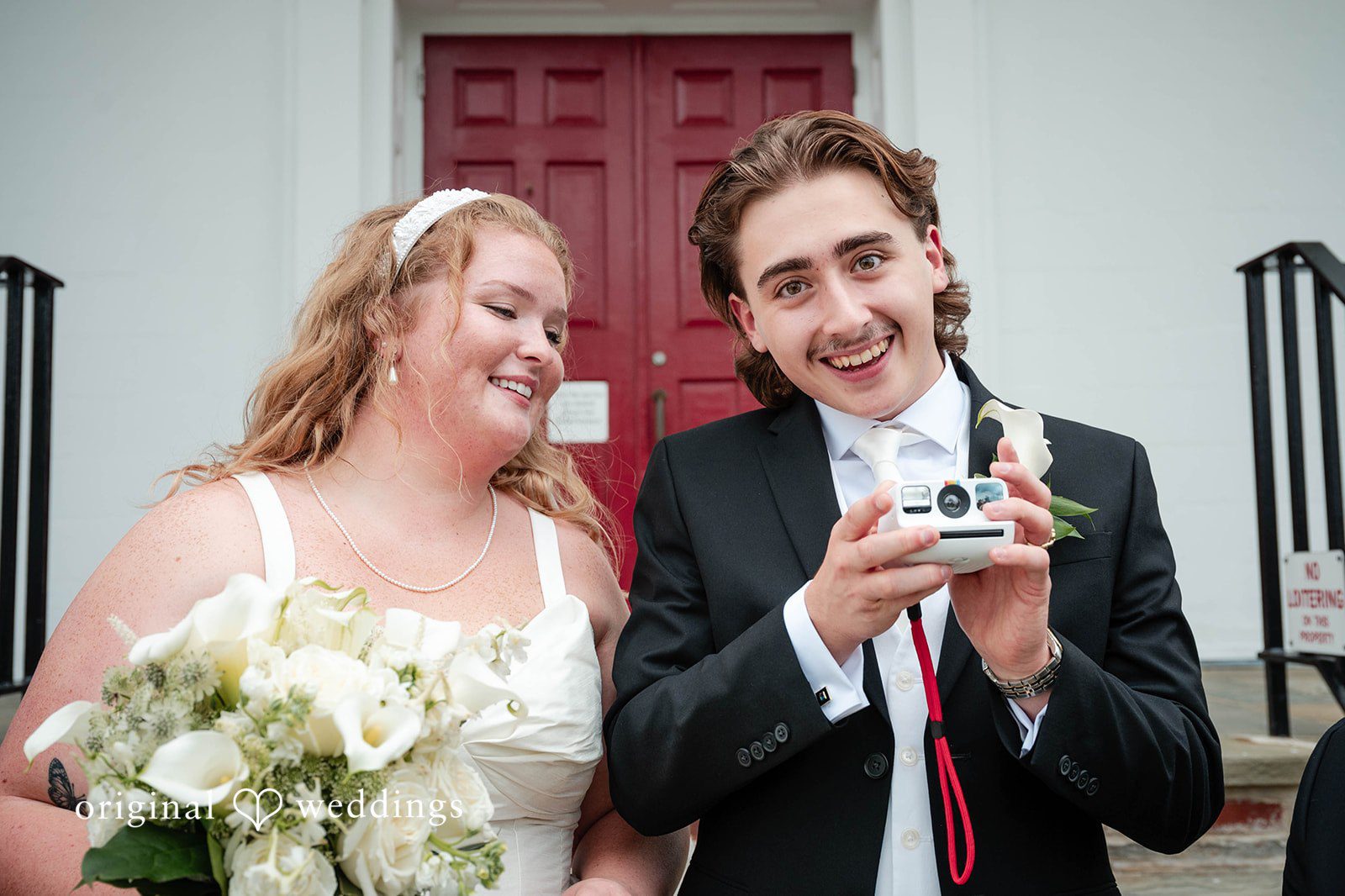 Bethany + Eddie Bride and groom laughing by the red church doors at Immanuel Orthodox Presbyterian Church