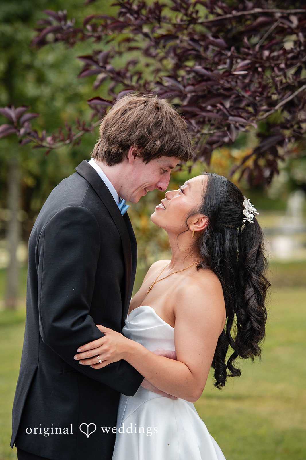 Mae + Corey A bride and groom share a close embrace while smiling at one another.