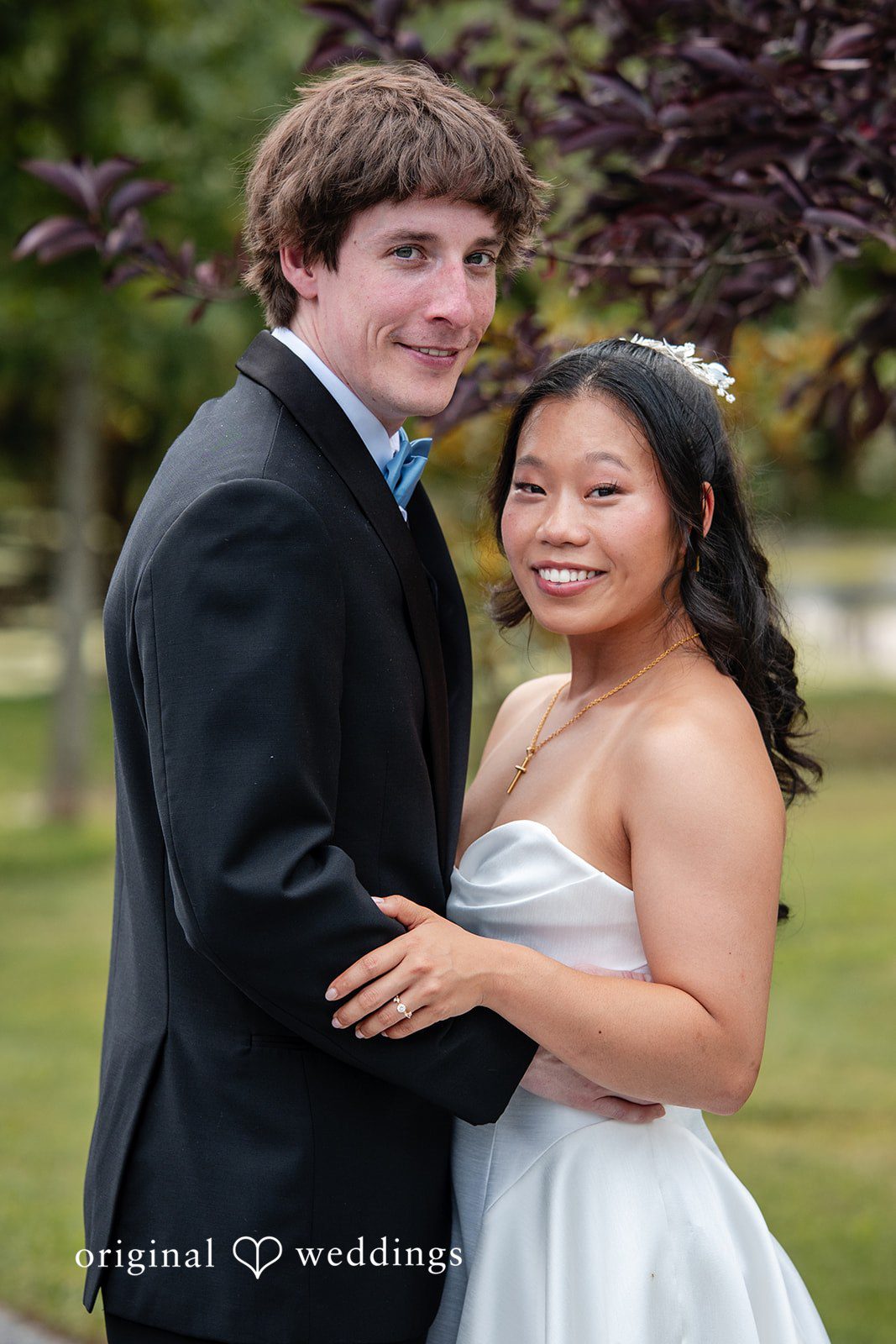 Mae + Corey A bride and groom pose closely together looking directly toward the camera.