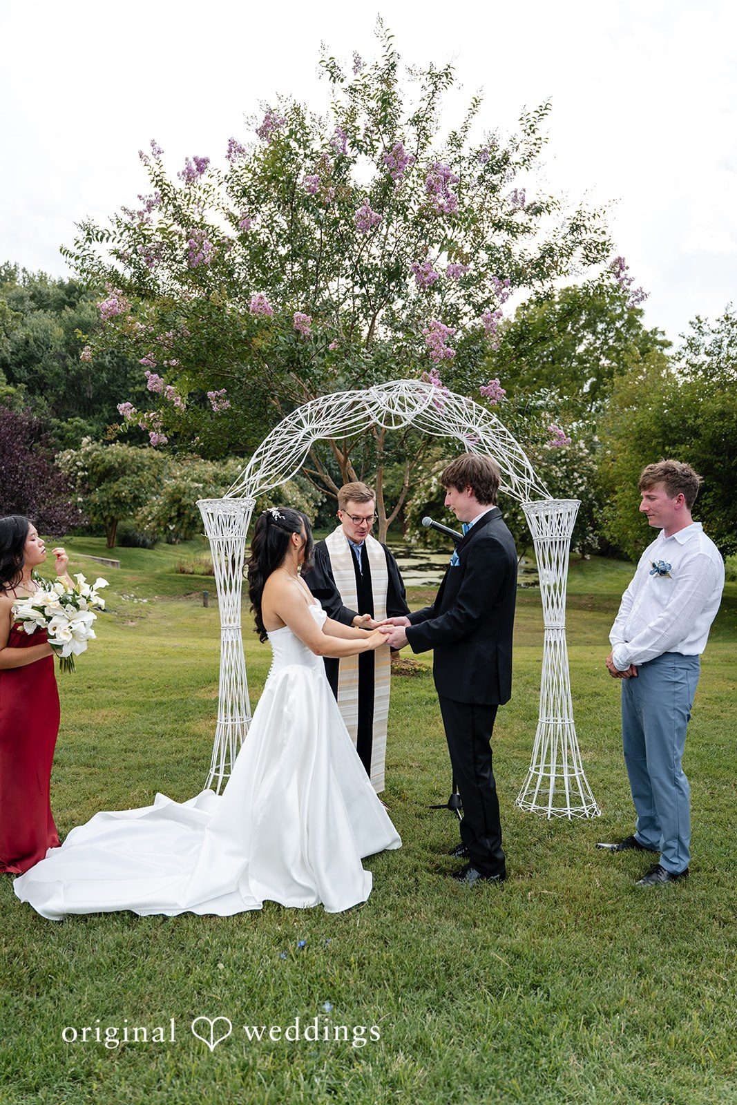 Mae + Corey A bride and groom stand at a decorated archway altar during their wedding ceremony.