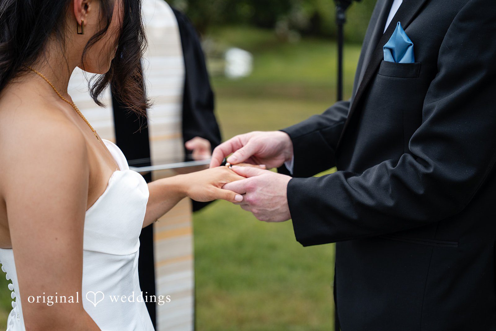 Mae + Corey A close-up shot of a groom placing a wedding ring onto a bride's finger.