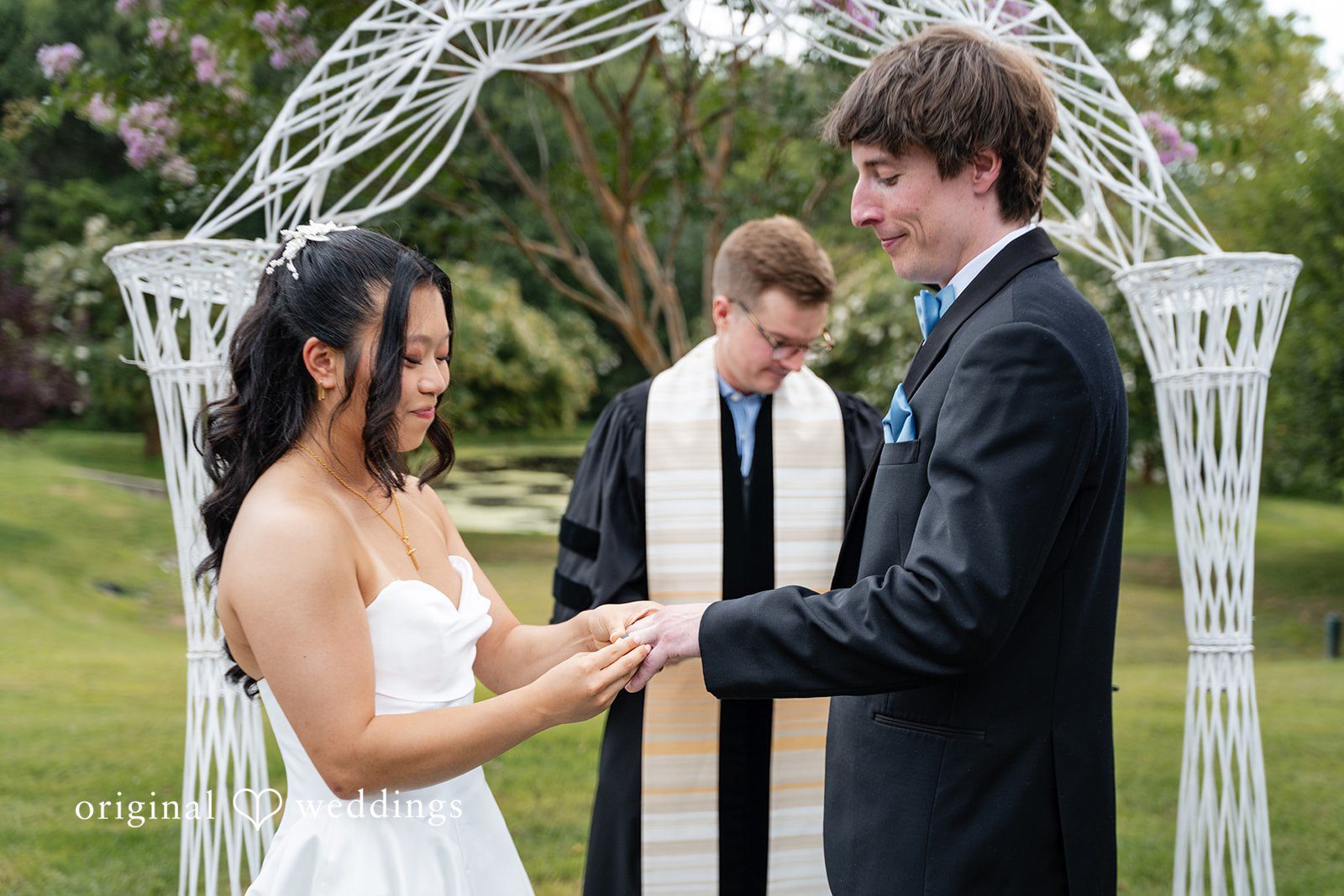 Mae + Corey A bride and groom stand before an officiant exchanging vows during a ceremony.