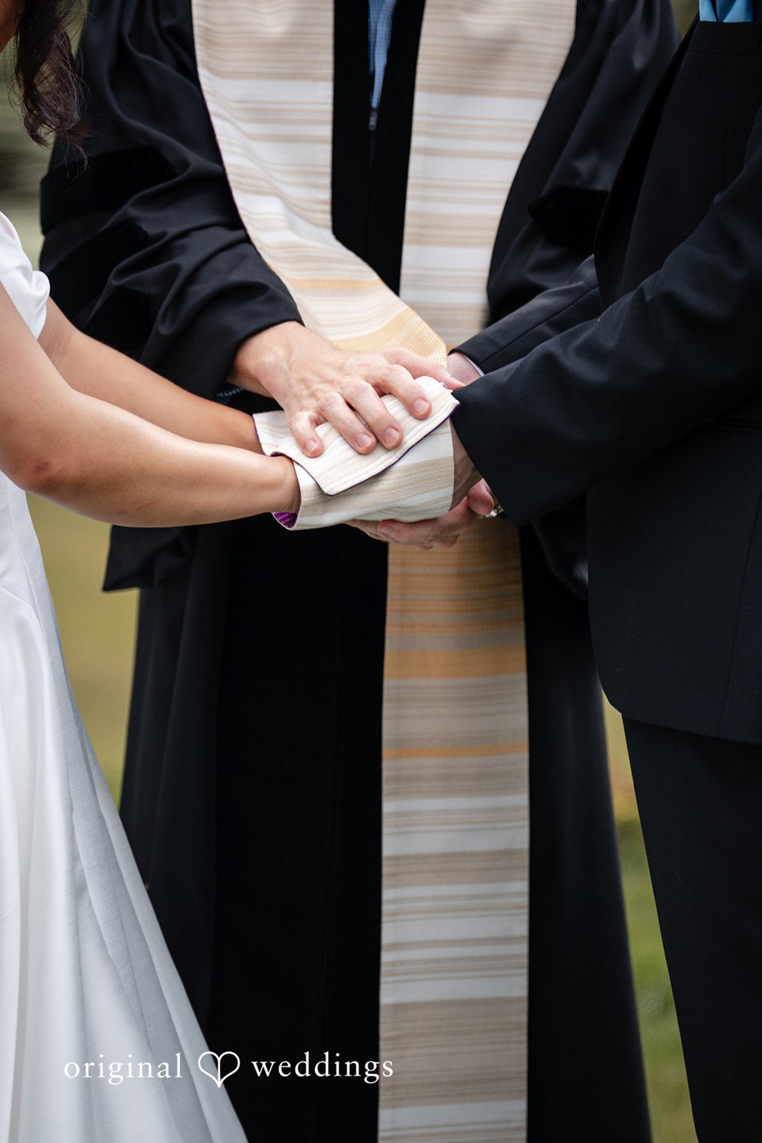 Mae + Corey A close-up view of a bride and groom holding hands during their wedding ceremony.