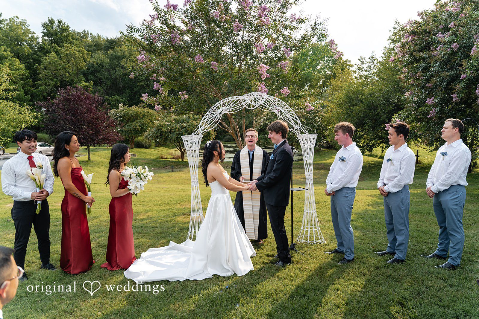 Mae + Corey A wide view of a wedding party standing at the altar surrounded by trees.