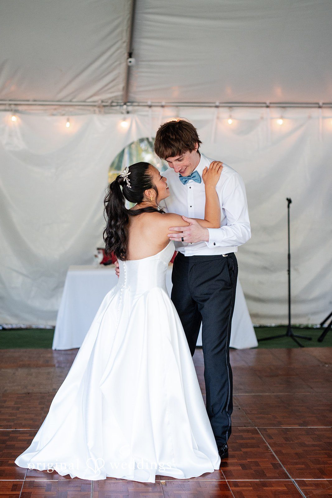 Mae + Corey A bride and groom share a slow dance together under a white reception tent.