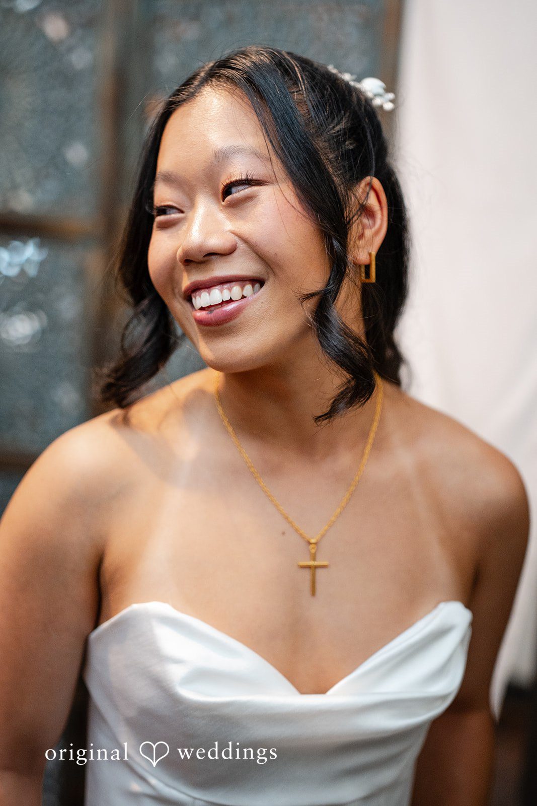 Mae + Corey A close-up portrait of a smiling bride wearing a white strapless wedding gown.