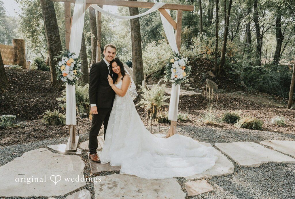 Lake Vadnais Grand Events Wedding | Jake & Ida 1 Ida and Jake posing under the floral ceremony arch, captured by Minneapolis wedding photographers from Original Weddings at Lake Vadnais Grand Events