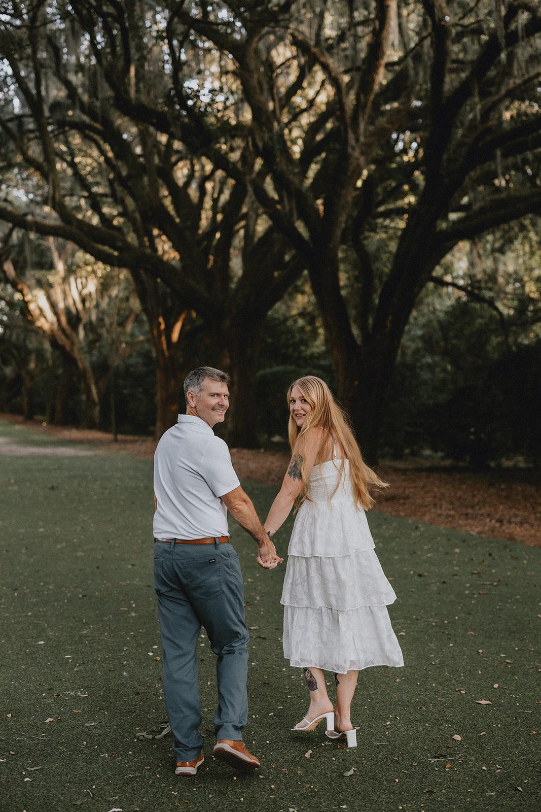 legare-waring-house-rustic-charleston-kaylee-nick-p004-06 Couple holding hands among the oaks