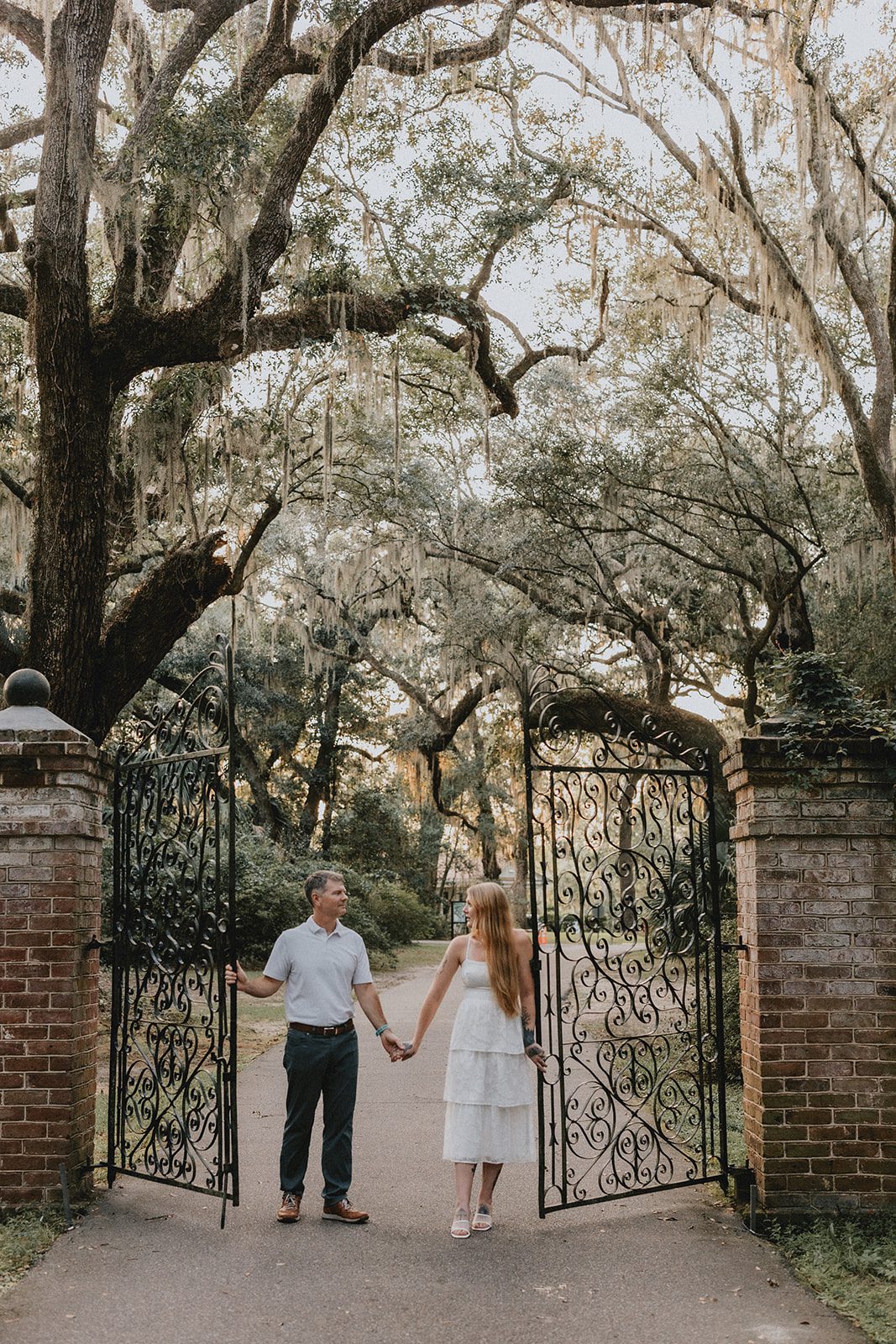 legare-waring-house-rustic-charleston-kaylee-nick-p020-07 Couple strolling down the avenue of oaks at Legare Waring House