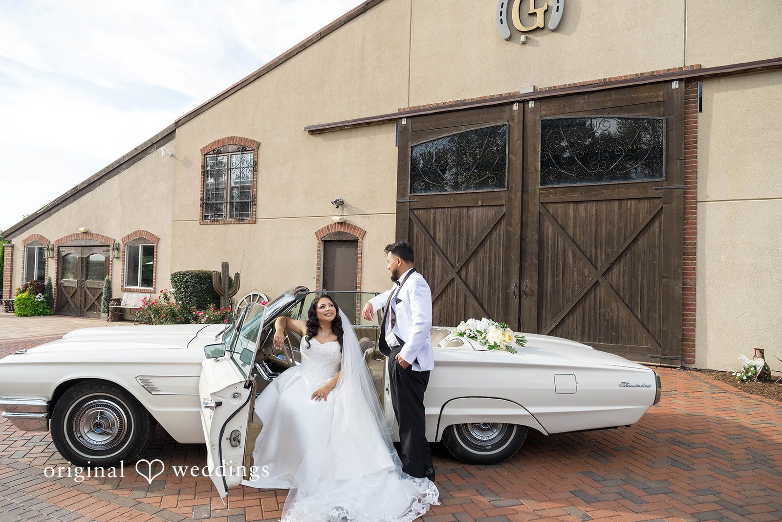 September 12, 2026 – Sierra & Arturo – (ID-4123) Bride and groom with a vintage white car and barn doors behind them, captured by Chicago wedding photographers from Original Weddings at Rancho Los Guzman